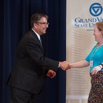 Doctor Smart shaking hands with an award receipient in a bright blue shirt